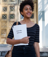 Young professional carrying paperwork and smiling.